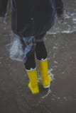 Person Wearing Clear Plastic Raincoat and Pair of Yellow Rainboots Stock Images Person Wearing Clear Plastic Raincoat and Pair of Yellow Rainboots Stock Images