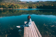 Persona que se sienta en par por el lago foto de archivo libre de regalías Persona que se sienta en par por el lago foto de archivo libre de regalías