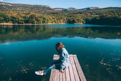 Persona que se sienta en par por el lago foto de archivo Persona que se sienta en par por el lago foto de archivo