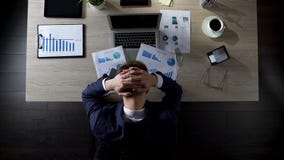 Persona trastornada del negocio que se sienta en la oficina y que piensa en las deudas, quiebra fotografía de archivo libre de regalías Persona trastornada del negocio que se sienta en la oficina y que piensa en las deudas, quiebra fotografía de archivo libre de regalías