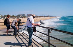 Personas que practica surf de la película del equipo de filmación en el Océano Pacífico del embarcadero del Huntington Beach imágenes de archivo libres de regalías Personas que practica surf de la película del equipo de filmación en el Océano Pacífico del embarcadero del Huntington Beach imágenes de archivo libres de regalías
