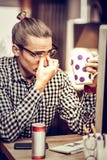 Personne masculine blonde fatiguée regardant sa tasse photo libre de droits Personne masculine blonde fatiguée regardant sa tasse photo libre de droits
