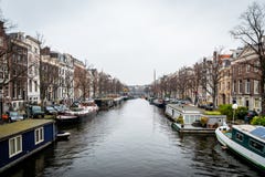 Perspektivstadssikt av byggnader och många husbåtar på en kanal i Amsterdam royaltyfri bild Perspektivstadssikt av byggnader och många husbåtar på en kanal i Amsterdam royaltyfri bild