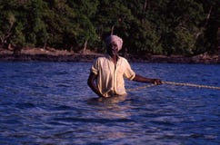 Perto de Port Blair, ilhas de Andaman, Índia, cerca do outubro de 2002: Pescador que puxa a rede de pesca do oceano imagens de stock Perto de Port Blair, ilhas de Andaman, Índia, cerca do outubro de 2002: Pescador que puxa a rede de pesca do oceano imagens de stock