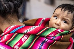 Peruanische einheimische Mutter bringt ihren Babysohn auf ihr zurück lizenzfreies stockfoto Peruanische einheimische Mutter bringt ihren Babysohn auf ihr zurück lizenzfreies stockfoto