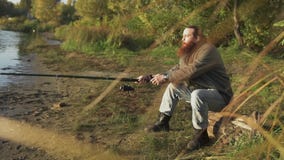 Pescador com pesca longa da barba no banco de rio Homem que espera emocionalmente os peixes Pesca do rio video estoque Pescador com pesca longa da barba no banco de rio Homem que espera emocionalmente os peixes Pesca do rio video estoque