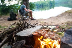 Pescatore che prepara cena su fuoco di accampamento, vacanza di campeggio di pesca di stile di vita di avventura fotografie stock Pescatore che prepara cena su fuoco di accampamento, vacanza di campeggio di pesca di stile di vita di avventura fotografie stock