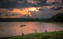 Pescatore che rema canoa nel tramonto nel lago Cheloor immagine stock Pescatore che rema canoa nel tramonto nel lago Cheloor immagine stock