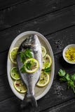 Pesce fresco di Dorado con il limone, la limetta ed il prezzemolo su un piatto ovale immagini stock libere da diritti Pesce fresco di Dorado con il limone, la limetta ed il prezzemolo su un piatto ovale immagini stock libere da diritti