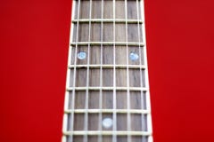 Pescoço em um fundo vermelho, foco seletivo da guitarra do close-up fotografia de stock royalty free Pescoço em um fundo vermelho, foco seletivo da guitarra do close-up fotografia de stock royalty free