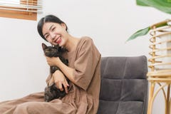 Pet Lover Concept, Young Asian Woman Sitting To Relax On Sofa On Floor To Playing And Hugging Cat Stock Photo