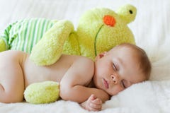 Petit bébé garçon, dormant avec la grande grenouille de nounours photographie stock Petit bébé garçon, dormant avec la grande grenouille de nounours photographie stock