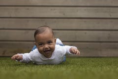 Petit bébé mignon adorable se trouvant sur le ventre sur la surface W d'herbe image stock Petit bébé mignon adorable se trouvant sur le ventre sur la surface W d'herbe image stock