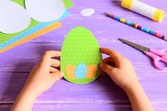 Petit enfant tenant une carte de Pâques dans des mains L'enfant a fait la carte de voeux de Pâques dans la forme d'oeufs photo libre de droits Petit enfant tenant une carte de Pâques dans des mains L'enfant a fait la carte de voeux de Pâques dans la forme d'oeufs photo libre de droits