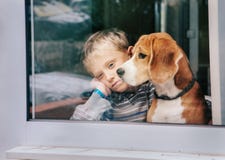 Petit garçon de peine avec le meilleur ami regardant par la fenêtre photo libre de droits Petit garçon de peine avec le meilleur ami regardant par la fenêtre photo libre de droits
