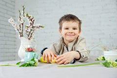 Petit garçon de sourire mignon peignant des oeufs de pâques sur le fond blanc photos stock Petit garçon de sourire mignon peignant des oeufs de pâques sur le fond blanc photos stock