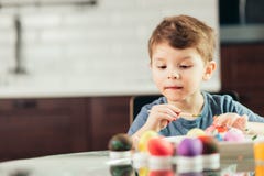 Petit garçon heureux peignant des oeufs de pâques, des enfants et la créativité photos libres de droits Petit garçon heureux peignant des oeufs de pâques, des enfants et la créativité photos libres de droits