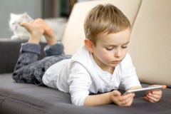 Petit garçon mignon utilisant l'application de voix de smartphone à la maison et la détente Enfant futé heureux jouant le jeu au photographie stock libre de droits Petit garçon mignon utilisant l'application de voix de smartphone à la maison et la détente Enfant futé heureux jouant le jeu au photographie stock libre de droits
