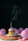 Petit gâteau de joyeux anniversaire avec une bougie soufflée sur un fond noir avec des ballons photos libres de droits Petit gâteau de joyeux anniversaire avec une bougie soufflée sur un fond noir avec des ballons photos libres de droits