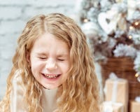 Petite fille blonde adorable avec les yeux fermés riant, Noël photographie stock Petite fille blonde adorable avec les yeux fermés riant, Noël photographie stock