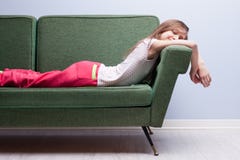 Petite fille dormant doucement sur un sofa vert Image stock Petite fille dormant doucement sur un sofa vert Image stock