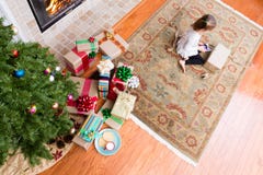 Petite fille enveloppant des cadeaux de Noël dans son salon image stock Petite fille enveloppant des cadeaux de Noël dans son salon image stock