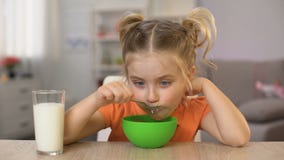 Petite fille heureuse mangeant des cornflakes avec la table à la maison se reposante de lait, nourriture saine banque de vidéos Petite fille heureuse mangeant des cornflakes avec la table à la maison se reposante de lait, nourriture saine banque de vidéos