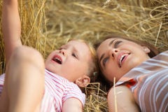 Petite fille mignonne avec la jeune mère se situant dans le domaine de blé image libre de droits Petite fille mignonne avec la jeune mère se situant dans le domaine de blé image libre de droits