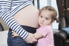 Petite fille mignonne embrassant sa mère enceinte image libre de droits Petite fille mignonne embrassant sa mère enceinte image libre de droits