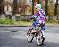 Petite fille montant une bicyclette en parc d'automne photos libres de droits Petite fille montant une bicyclette en parc d'automne photos libres de droits