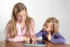 Petites filles jouant sur un dispositif de calcul de tablette image libre de droits Petites filles jouant sur un dispositif de calcul de tablette image libre de droits