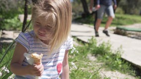 Peu blonde de fille mange la crème glacée dans une tasse de gaufre un jour chaud banque de vidéos Peu blonde de fille mange la crème glacée dans une tasse de gaufre un jour chaud banque de vidéos