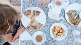 Peu de fille mange des crêpes pour les mains de la maman de petit déjeuner les a coupées en morceaux banque de vidéos Peu de fille mange des crêpes pour les mains de la maman de petit déjeuner les a coupées en morceaux banque de vidéos
