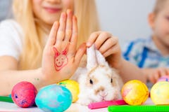Peu de lapin de lapin avec les oeufs et les marqueurs colorés sur la table fille et garçon blonds sur le fond Prepearing pour Pâq image libre de droits Peu de lapin de lapin avec les oeufs et les marqueurs colorés sur la table fille et garçon blonds sur le fond Prepearing pour Pâq image libre de droits