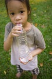 Peu eau potable d'enfants de bouteille en parc vert photos libres de droits Peu eau potable d'enfants de bouteille en parc vert photos libres de droits