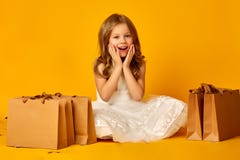 Peu fille étonnée tient des sacs sur le fond jaune photo stock Peu fille étonnée tient des sacs sur le fond jaune photo stock