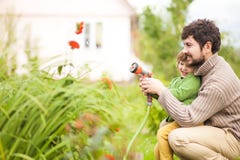 Peutermeisje en haar vader die de tuin water geven en pret hebben stock fotografie Peutermeisje en haar vader die de tuin water geven en pret hebben stock fotografie