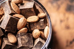 Pezzi di cioccolato amaro scuro con cacao e le mandorle matte su fondo di legno Concetto degli ingredienti della confetteria fotografia stock Pezzi di cioccolato amaro scuro con cacao e le mandorle matte su fondo di legno Concetto degli ingredienti della confetteria fotografia stock