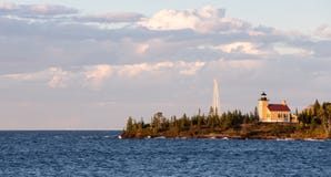 Phare et nuages de collecte dans la lumière de soirée Photo stock Phare et nuages de collecte dans la lumière de soirée Photo stock