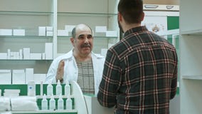 Pharmacien supérieur positif donnant la médecine de client à la pharmacie image stock Pharmacien supérieur positif donnant la médecine de client à la pharmacie image stock