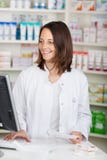 Pharmacien Using Computer While tenant le papier de prescription au De photos stock Pharmacien Using Computer While tenant le papier de prescription au De photos stock