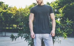 Photo Bearded Muscular Man Wearing Black Empty t-shirt and shorts in summer vacation. Relaxing time near the lake. Green. City Garden Park Sunset Background Stock Photography Photo Bearded Muscular Man Wearing Black Empty t-shirt and shorts in summer vacation. Relaxing time near the lake. Green. City Garden Park Sunset Background Stock Photography