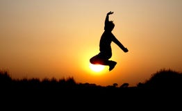 Photo de silhouette de sauter le jeune garçon masculin pendant le coucher du soleil image libre de droits Photo de silhouette de sauter le jeune garçon masculin pendant le coucher du soleil image libre de droits