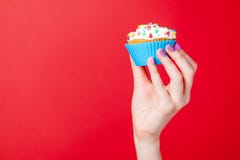 photo of female hand holding cupcake on the wonderful red background stock photo photo of female hand holding cupcake on the wonderful red background stock photo