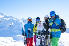 Photo of four sportsmen wearing helmet and holdingsnowboards at snow resort
