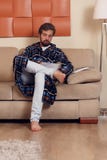 Photo of man in home dressing gown with magazine on couch