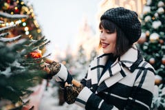Photo of young brunette near painted Christmas tree on street stock photo Photo of young brunette near painted Christmas tree on street stock photo