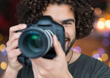 Photographer Smiling And Taking A Photo Foreground. City Blurred Lights Behind Royalty Free Stock Photos