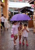 PHUKET, ΤΑΪΛΆΝΔΗ - 17 ΑΥΓΟΎΣΤΟΥ 2018: Παιδιά που περπατούν στη βροχή κάτω από μια ομπρέλα στη λεωφόρο αγορών Jungceylon στην πόλη στοκ φωτογραφίες PHUKET, ΤΑΪΛΆΝΔΗ - 17 ΑΥΓΟΎΣΤΟΥ 2018: Παιδιά που περπατούν στη βροχή κάτω από μια ομπρέλα στη λεωφόρο αγορών Jungceylon στην πόλη στοκ φωτογραφίες
