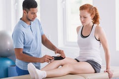 Physiotherapeut, der Bänder auf das Bein des Patienten während des Kinesiotapings setzt stockbild Physiotherapeut, der Bänder auf das Bein des Patienten während des Kinesiotapings setzt stockbild
